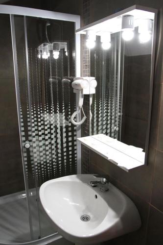 a bathroom with a sink and a shower and a mirror at Pensiunea Argesu ** in Sinaia