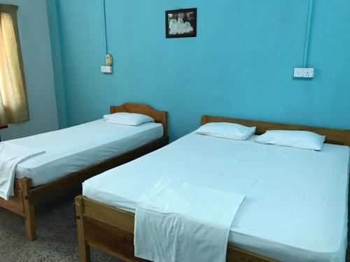 two beds in a room with blue walls at Gnaanams Hotel and Restaurant in Jaffna