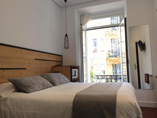 a bedroom with a large bed with a large window at Pensión La Perla in Donostia-San Sebastián