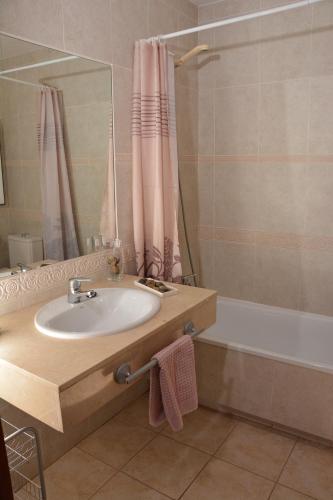 a bathroom with a sink and a tub and a mirror at Vv Tirma in Caleta De Fuste