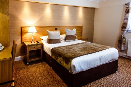 a hotel room with a large bed and a lamp at Adamson Hotel in Dunfermline