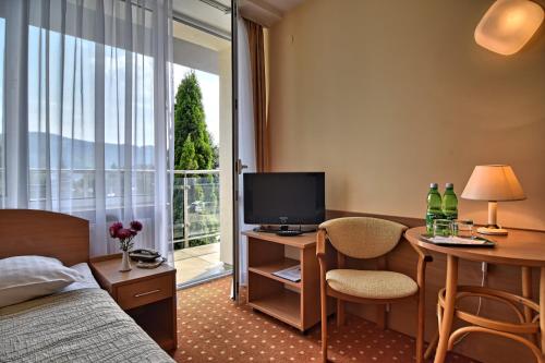 リトロにあるHotel Perła Południaのベッド、デスク、テレビが備わるホテルルームです。
