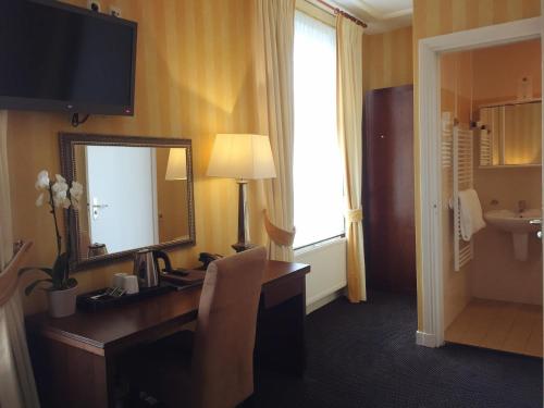 a hotel room with a desk and a mirror at Hotel Johannes Vermeer Delft in Delft