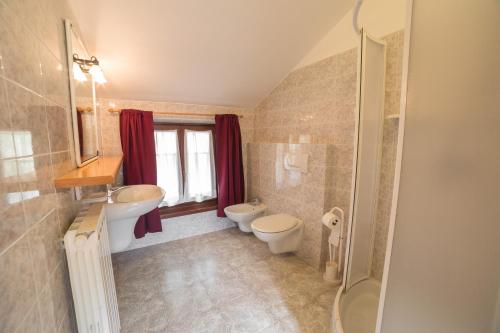 łazienka z 2 toaletami i umywalką w obiekcie Ca Serena Mansarda w mieście Ledro