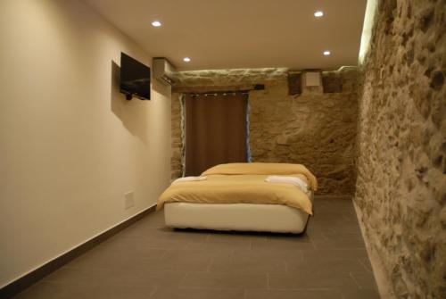 ein Schlafzimmer mit einem Bett und einer Steinmauer in der Unterkunft Yuba - Aragon home holiday in Montalbano Elicona
