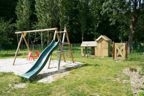 a playground with a green slide and a wooden swing at Gîtes du Vieux Presbytère in Baguer-Pican