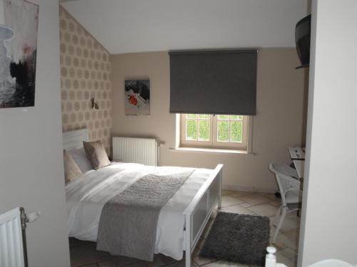 1 dormitorio con cama blanca y ventana en B&B De Polderhoeve en Blankenberge