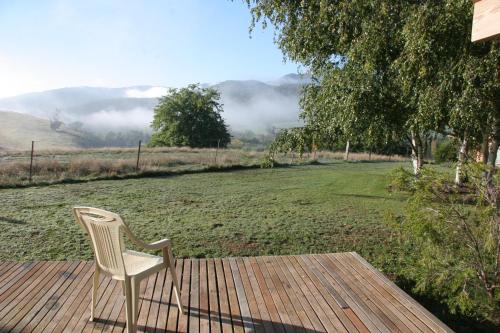 a white chair sitting on a wooden deck with a field at Jamieson Valley Retreat in Howqua