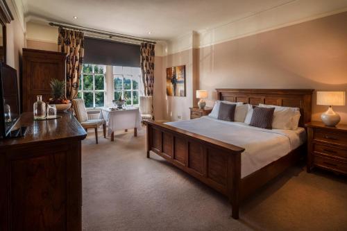 a bedroom with a large bed and a desk and a table at The Glencarn Hotel in Castleblayney