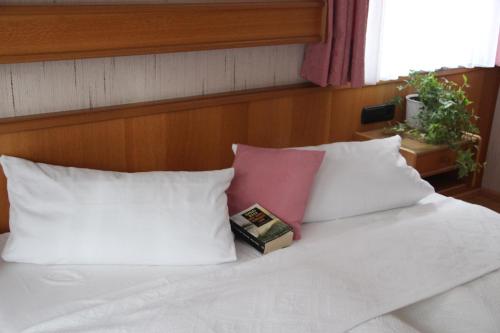 a bed with white pillows and a book on it at Gästehaus Heimenberg in Bad Rippoldsau-Schapbach