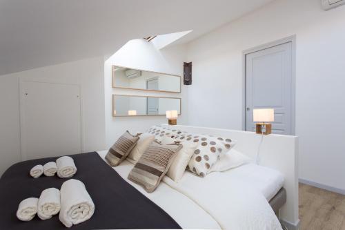 une chambre blanche avec un grand lit blanc avec des oreillers dans l'établissement Teisseire Accomodations, à Cannes