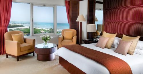 a hotel room with a bed and chairs and a large window at Danat Jebel Dhanna Resort in Jebel Dhanna