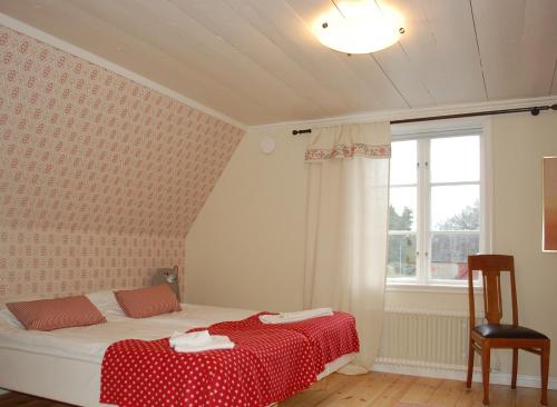 a bedroom with a bed with a red blanket and a window at Allégården Kastlösa Hotell in Kastlösa