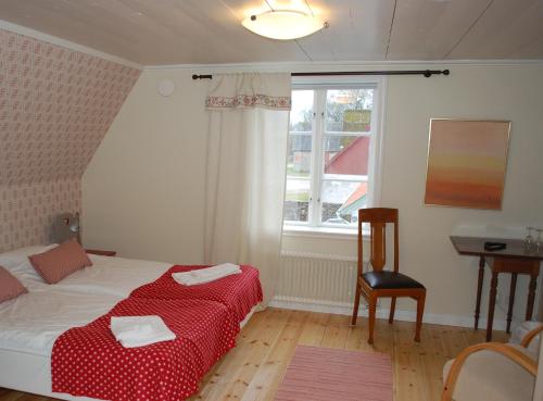 Schlafzimmer mit einem Bett, einem Tisch und einem Fenster in der Unterkunft Allégården Kastlösa Hotell in Kastlösa