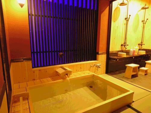 a bathroom with a large tub with a window at Yadoya in Kyoto
