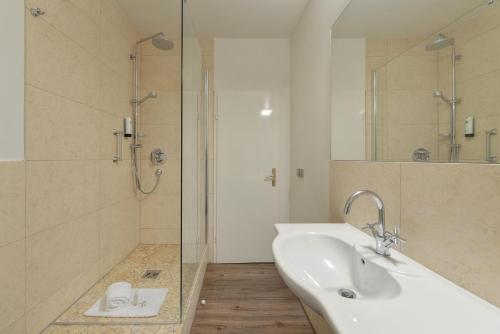 a white bathroom with a sink and a shower at Living am Carlsplatz Apartment in Düsseldorf