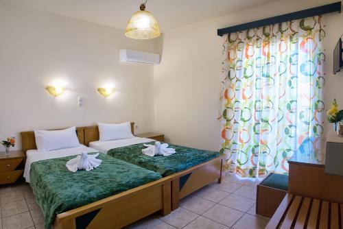 a hotel room with two beds and a window at Nicolas Hotel in Georgioupolis