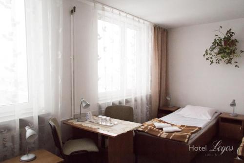 a room with a bed, desk, chair and window at Hotel Logos in Lublin
