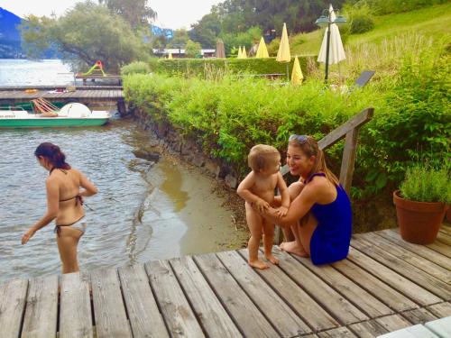 a woman and a child sitting on a dock at Waldstrand Berger in Seeboden