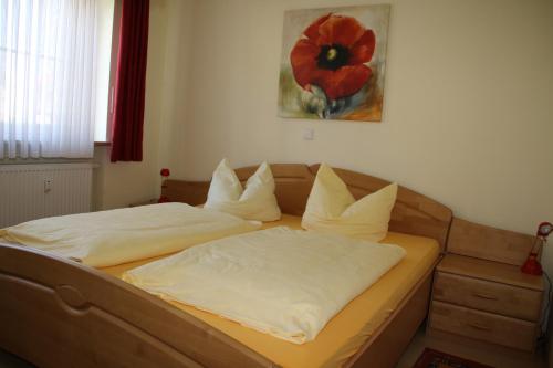 a bed with white sheets and a red flower on the wall at 2 Zimmer Kursuite Bad Füssing in Bad Füssing