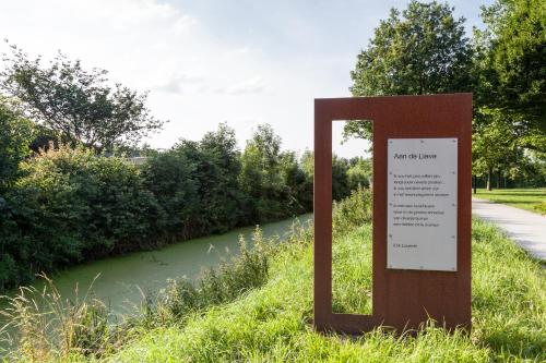 a sign in the grass next to a river at B&B De Lievde in Lievegem