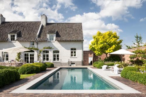 a swimming pool in front of a house at B&B De Lievde in Lievegem