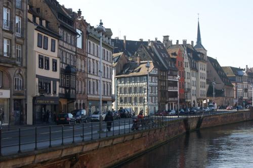 a group of buildings next to a river with cars at Quai 17 Maison d'hôtes in Strasbourg