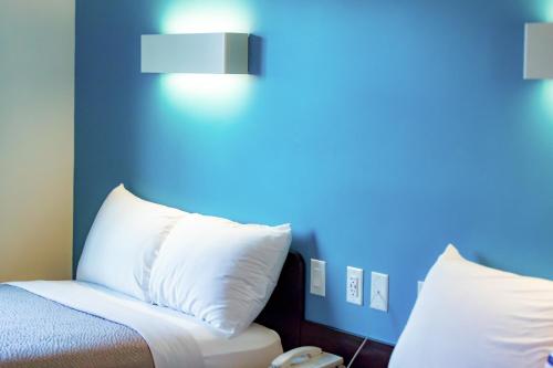 a bed with white pillows and a blue wall at Motel 6-Pottstown, PA in Pottstown