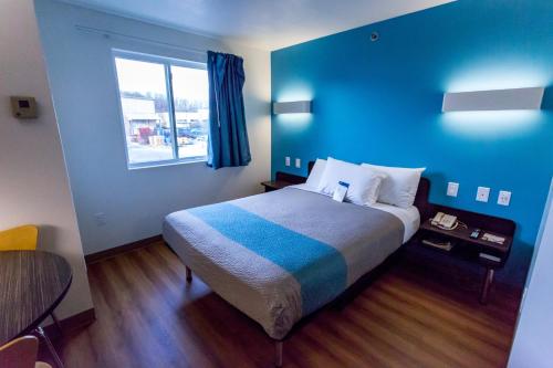 a bedroom with a bed with blue walls and a window at Motel 6-Pottstown, PA in Pottstown