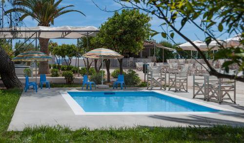 una piscina con sillas, sombrillas, mesa y sillas en The Grove Seaside Hotel en Drepano