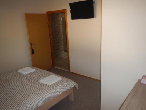 a bedroom with a bed and a television on the wall at Riverside Guesthouse in Počitelj