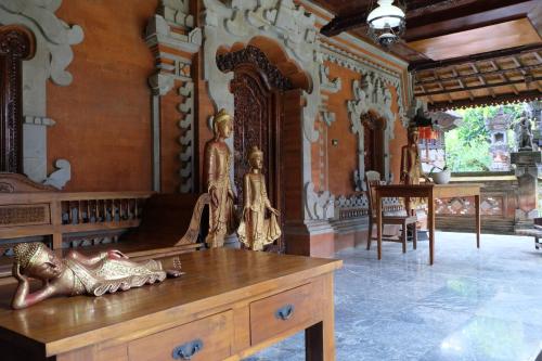 a room with a wooden table with statues on it at Adys Inn in Legian