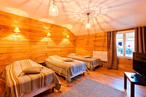two beds in a room with wooden walls at Clos De La Gourmandière in Saint-Lothain