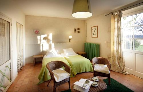 - une chambre avec un lit doté d'une couverture verte et de chaises dans l'établissement Chambres d'Hôtes Logis de l'Astrée, à Saint-Bris-des-Bois