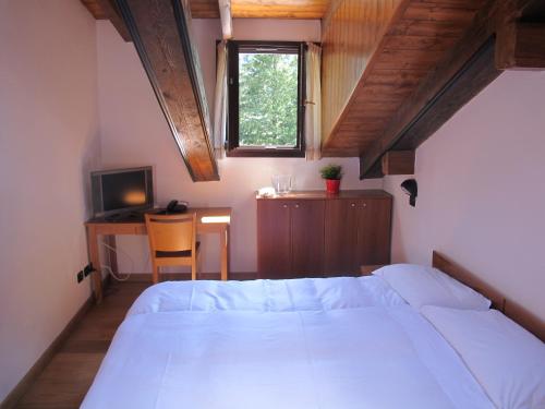 a bedroom with a bed and a desk and a window at Casa Alpina Don Guanella in Macugnaga