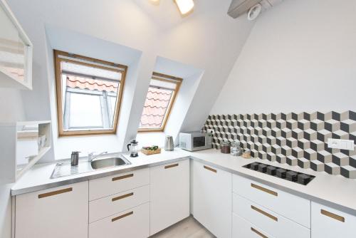 a kitchen with white cabinets and a checkered wall at Old Town Panorama Apartments in Gdańsk