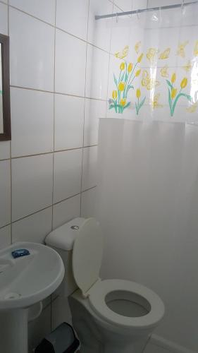 a white bathroom with a toilet and a sink at Hotel Bella Júlia in Joinville