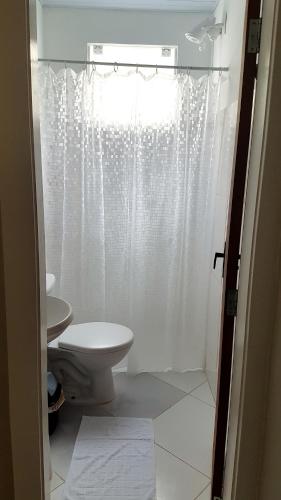 a bathroom with a toilet and a shower curtain at Hotel Bella Júlia in Joinville