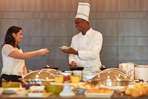 a man and a woman standing in a kitchen at Novotel RJ Santos Dumont in Rio de Janeiro