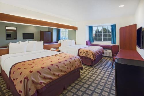 a hotel room with two beds and a television at Microtel Inn & Suites by Wyndham Holland in Holland