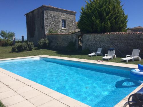 une piscine avec deux chaises et un bâtiment dans l'établissement Chambres d'Hôtes Logis de l'Astrée, à Saint-Bris-des-Bois