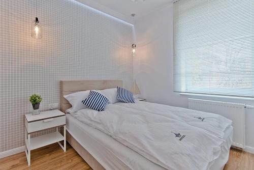 biała sypialnia z łóżkiem i stolikiem nocnym w obiekcie Imperial Apartments - Balticana w mieście Sopot