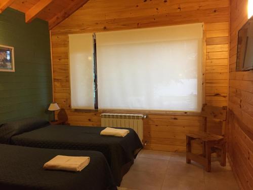 a room with two beds and a window in a cabin at Encanto del Rio in Villa La Angostura