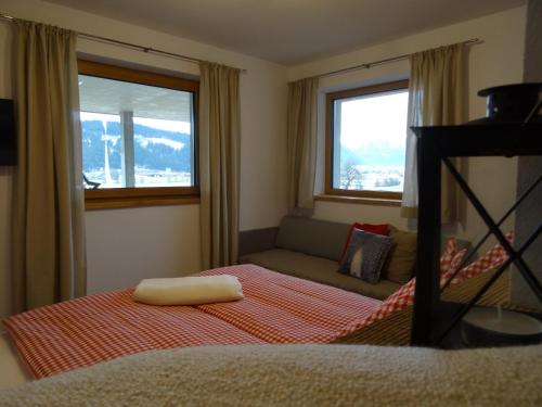 a bedroom with a bed and a couch and two windows at Appartement Hoamatgfühl in Flachau