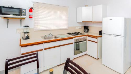 a kitchen with a white refrigerator and a sink at Bougainvillea Apartments in Saint Georgeʼs