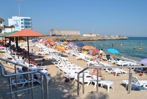 a beach with chairs and umbrellas and people on the beach at Kompleks Otdykha Elki-Palki in Odesa