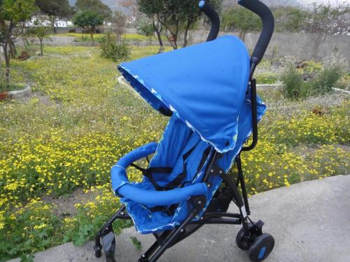 a blue stroller sitting on a sidewalk in a park at JB Villa in Mesaria
