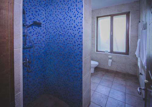 y baño con ducha de azulejos azules y aseo. en Marshal Resort Kobuleti, en Kobuleti