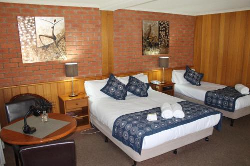 a hotel room with two beds and a table with a desk at Bakery Hill Motel in Ballarat