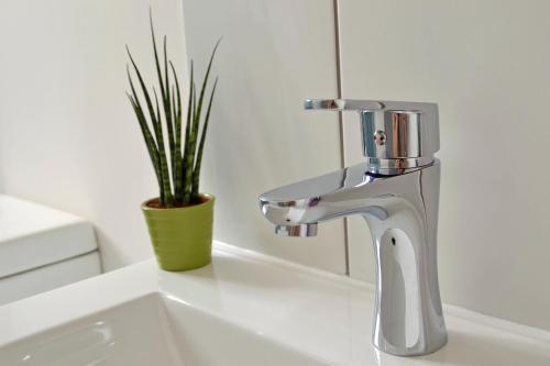 a bathroom sink with a faucet and a plant at Athena Holiday Homes in Limassol